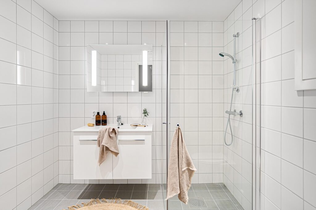jolie salle de bain blanche avec une douche sans marche pour senior