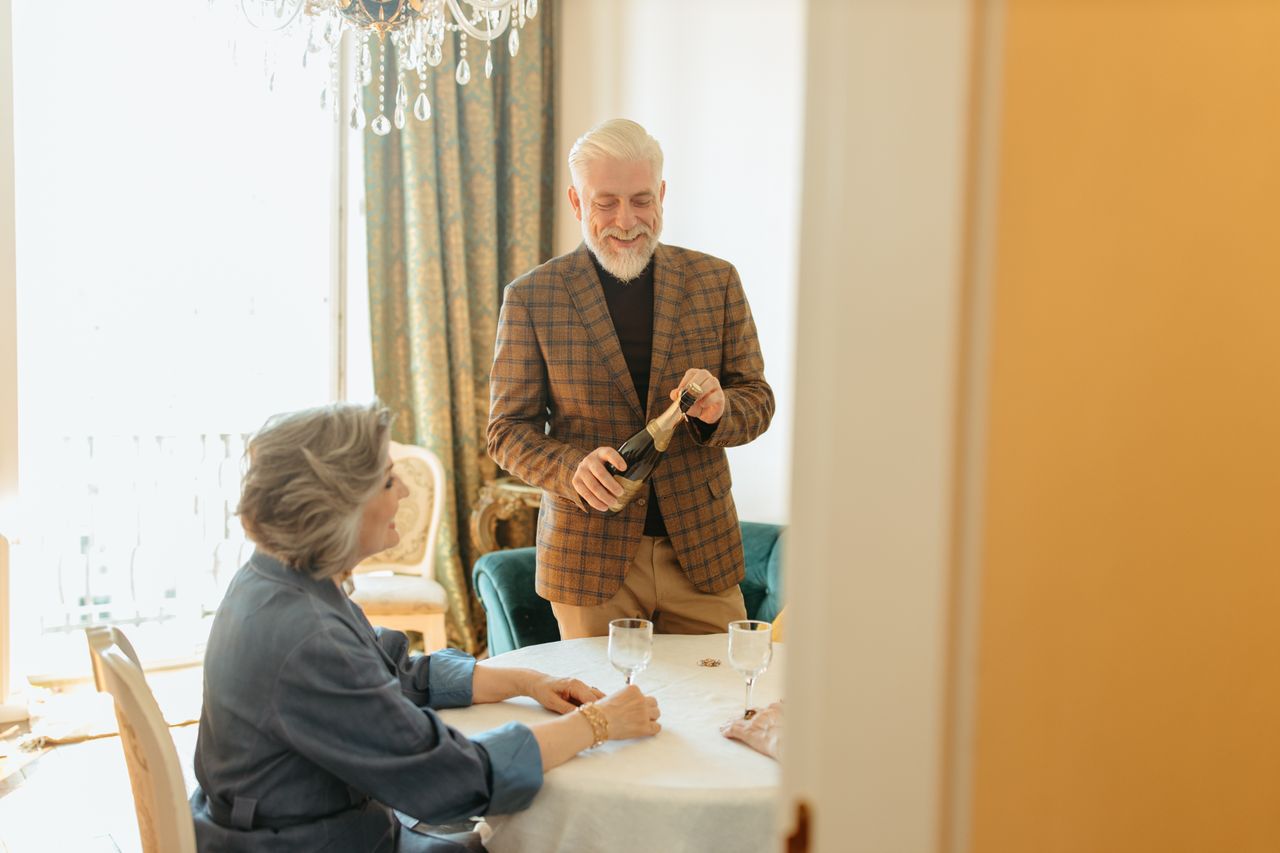 Mastering the First Impression: Your intriguing post title goes here Elderly couple sharing a joyful moment with wine in a cozy indoor setting.