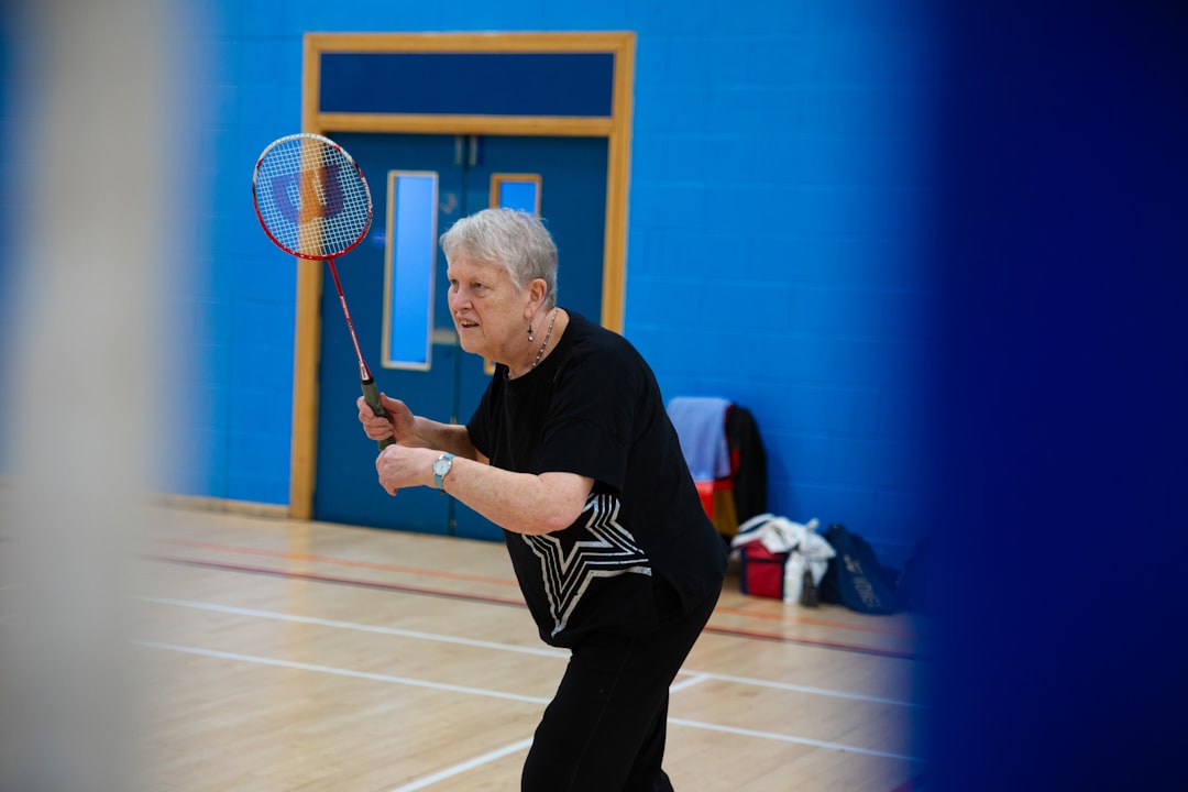 contact-img elderly-woman-playing-badminton-in-a-gymnasium-1twzjqzgcku